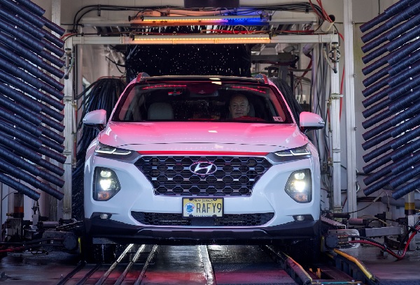Image of a white SUV coming through the car wash, front angle